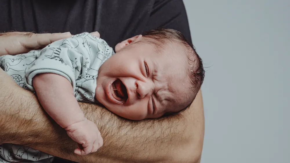Schreiendes Baby wird auf dem Arm getragen: Hilfe bei Schreibaby und Regulationsstörung