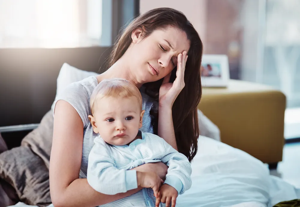 Erschöpfte Mutter hält ihr Baby im Arm